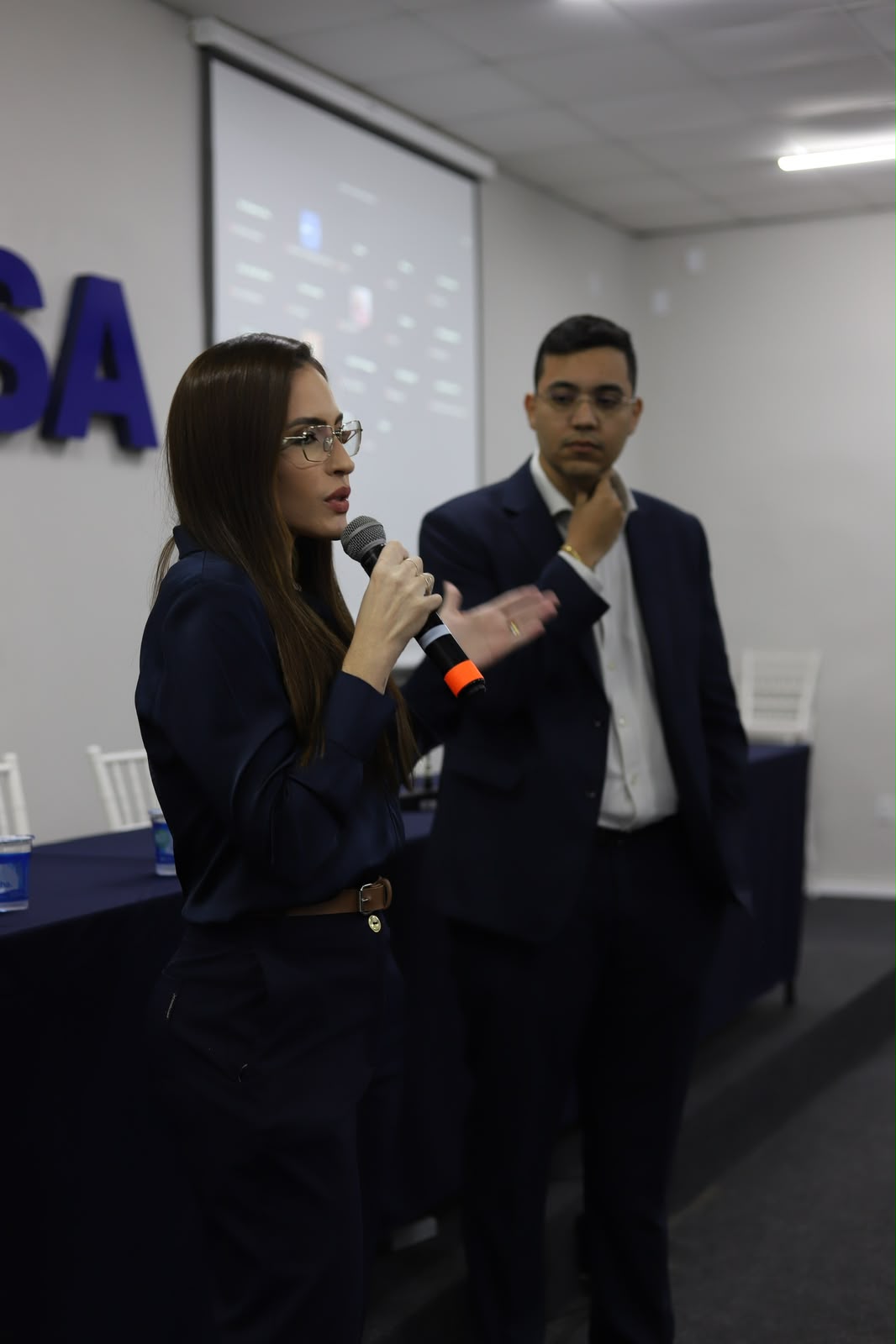 Dra. Stephany Quintanilha ao microfone em palestra institucional